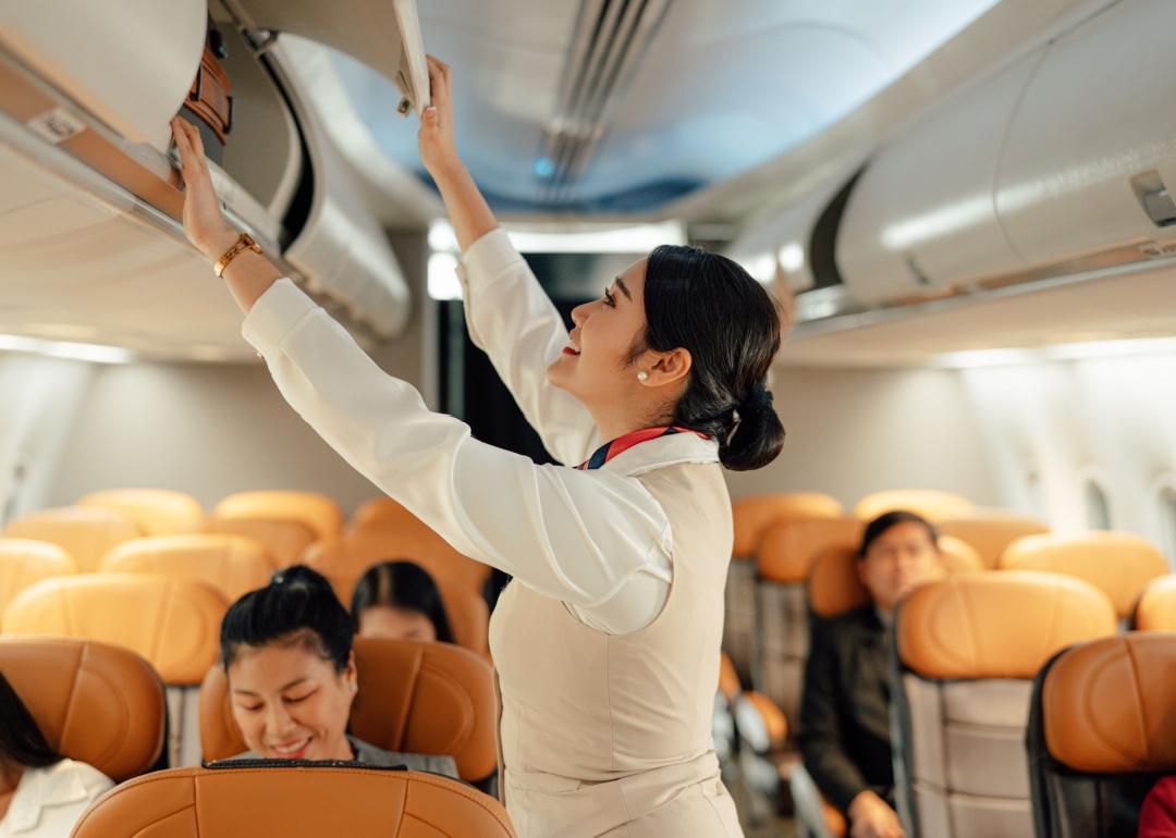 Flight attendant adjusting overhead bin