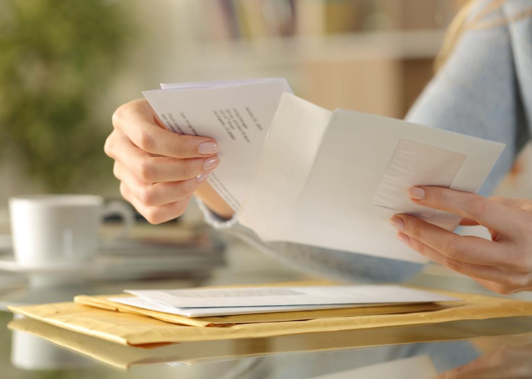 Hands opening an envelope with a letter inside.