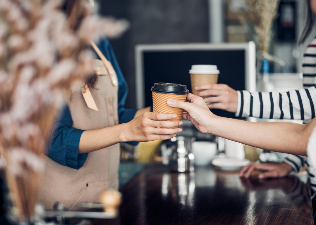 Barista serving drink in to go cup at counter.