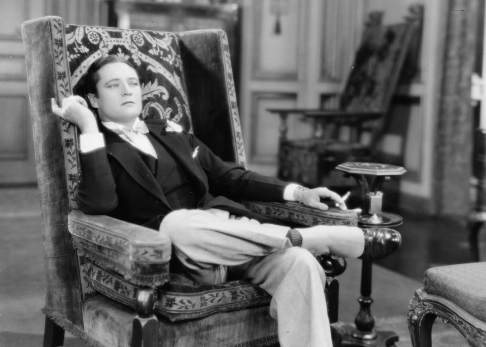 Actor Edmund Lowe seated in a chair beside smoking stand in a scene from 'Soul Mates’.