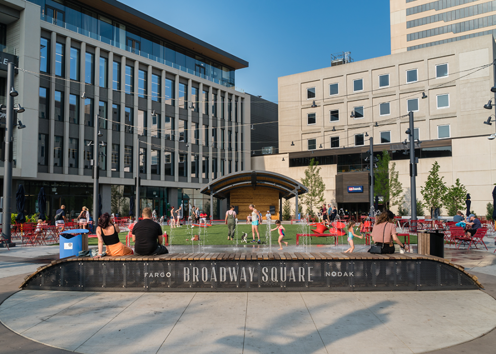 People gather around public fountain on a hot summer day at Broadway Square.