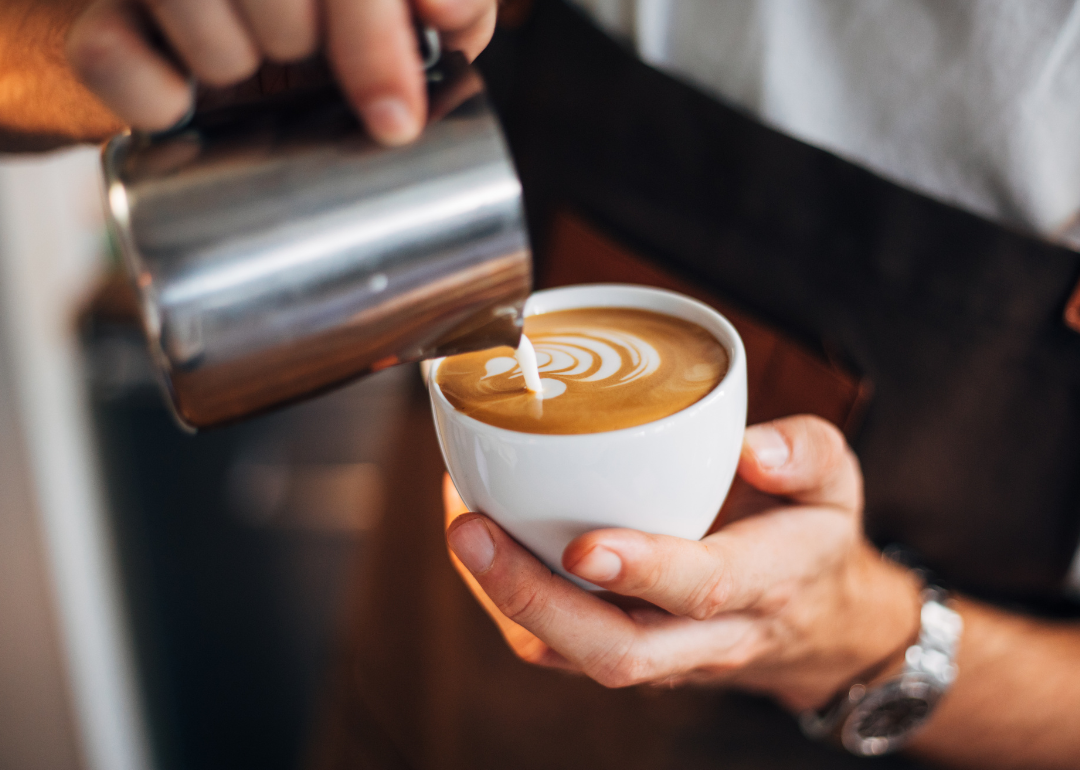 Barista pouring milk into cup.