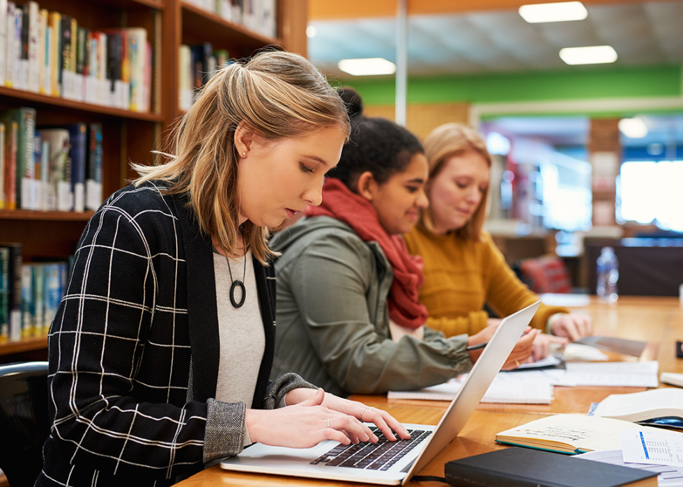 Students working on a laptop in the library.