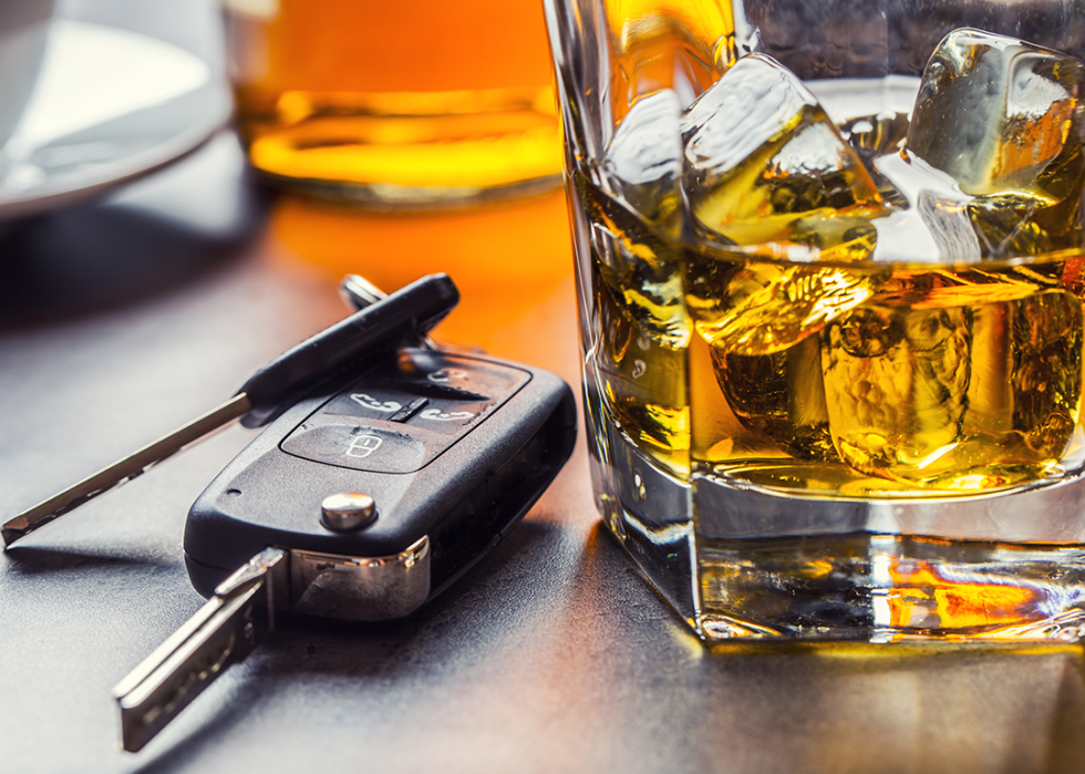 Car keys and a glass of alcohol on a table.