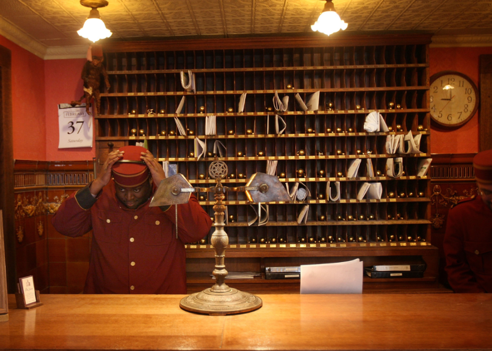A bellhop adjusts his hat at the front desk of The Jane Hotel.