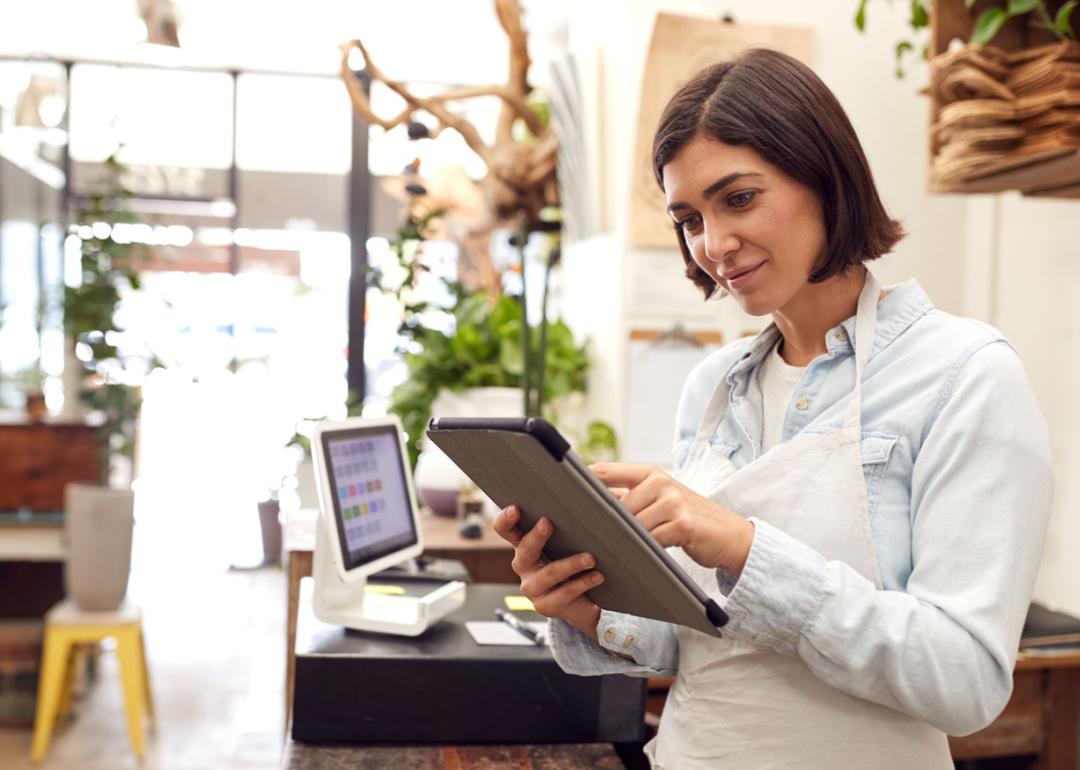 Business owner with digital tablet standing behind sales desk.