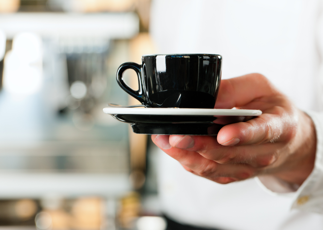Close-up barista presenting espresso drink.