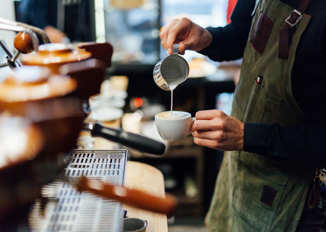 Barista pours milk in coffee drink