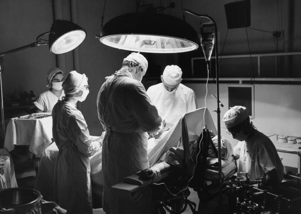 Surgeons and nurses with patent in operating room.
