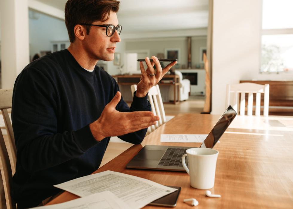 Man talking on speakerphone working from home.