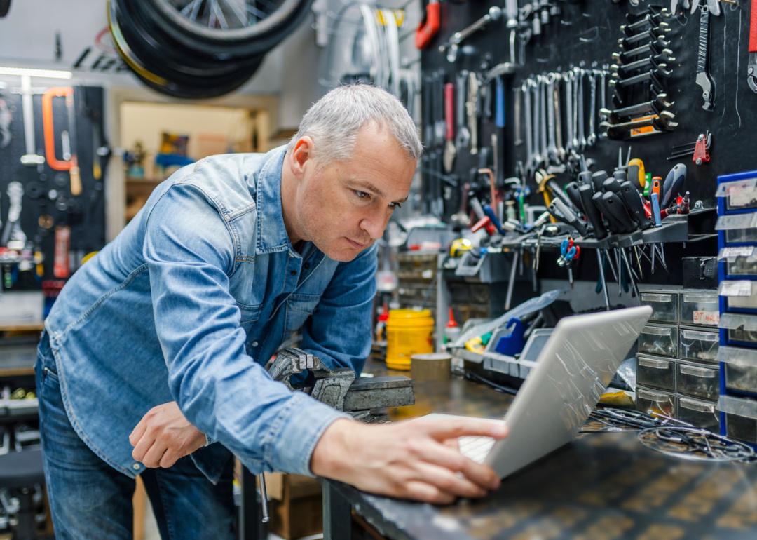 Male shop owner looking at laptop.