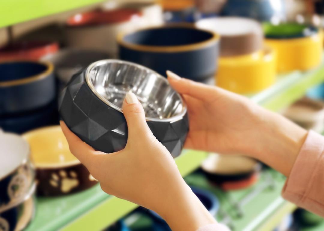 Hands of person selecting bowl in pet shop.