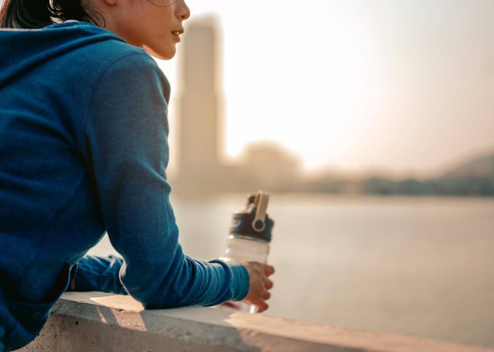 Woman pausing to drink water admiring city view