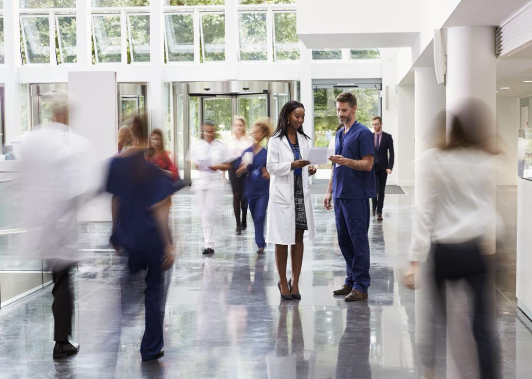 Medical staff reviewing a document in a busy hospital lobby.