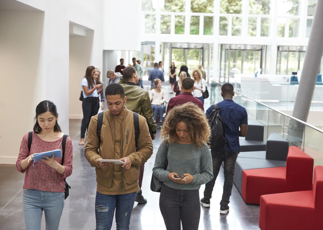 Students walk in university campus with phones