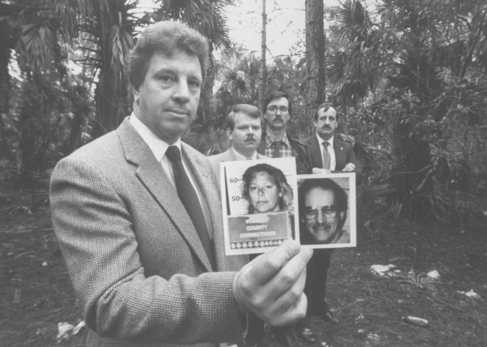 Investigator holds mugshot of murderer Aileen Wuornos and image of victim