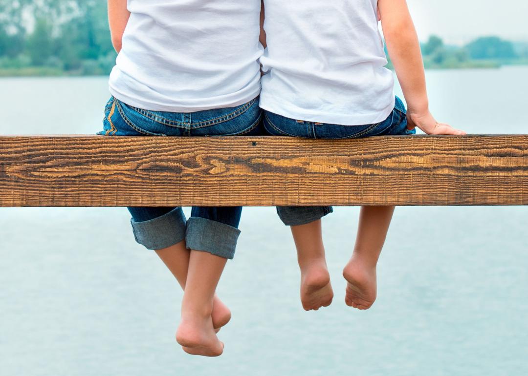 Two brothers sitting on pier by water
