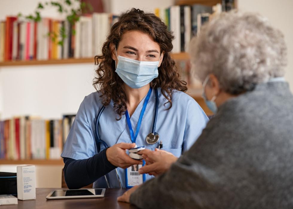 A medical professional checking oximeter on senior patient.