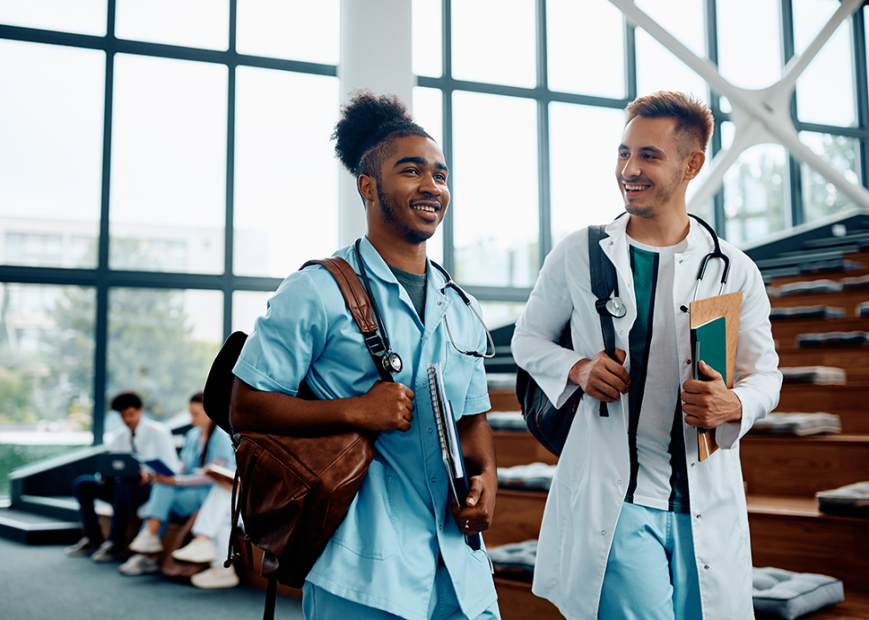 Two medical students walking in bright, naturally lit classroom.