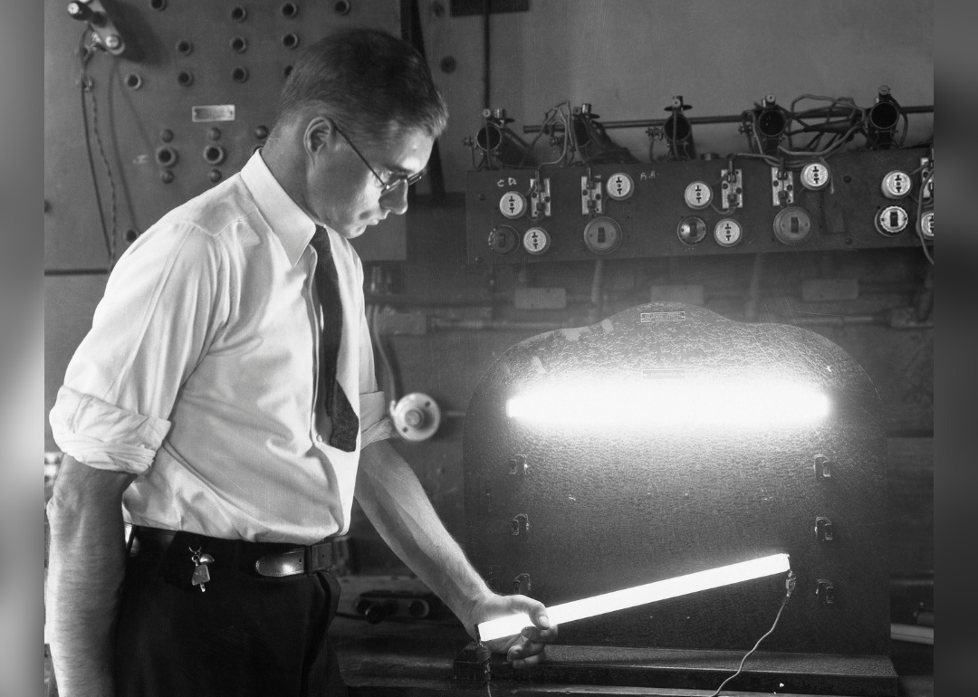 A man demonstrates a flourescent lamp.