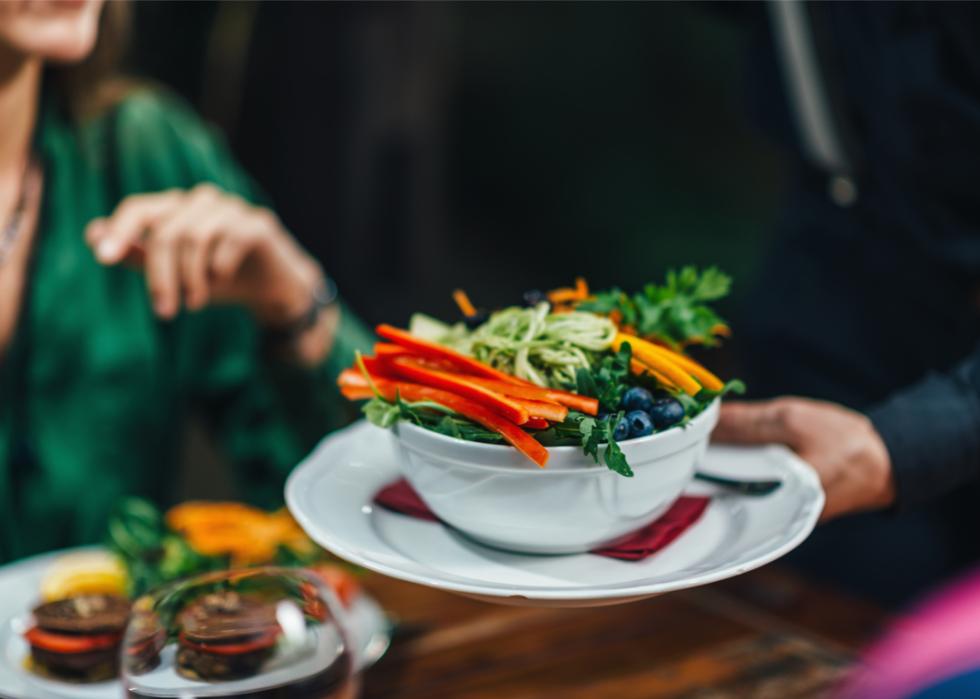 Waiter serving plate of healthy food to patron