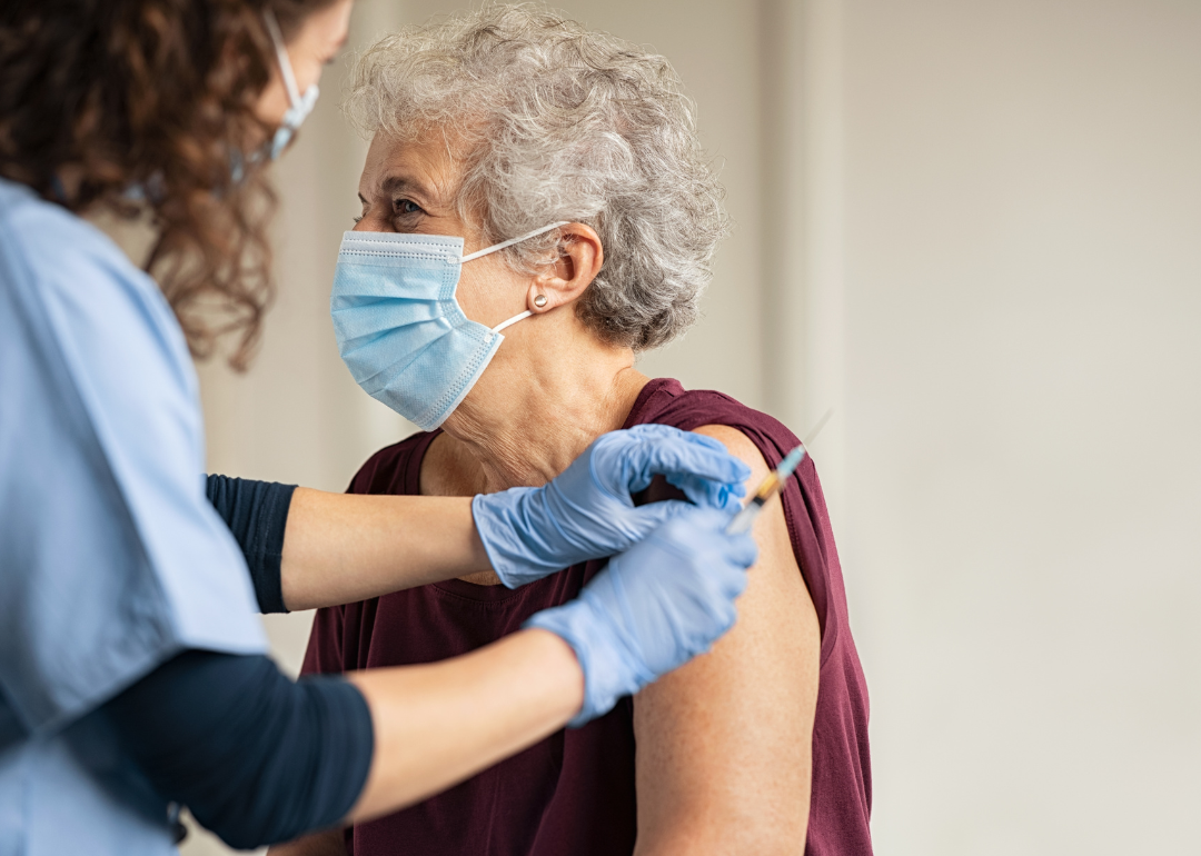 Nurse vaccinating senior patient.