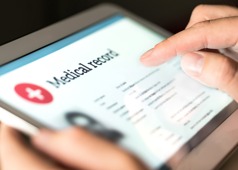 Hand holding digital tablet with medical record.