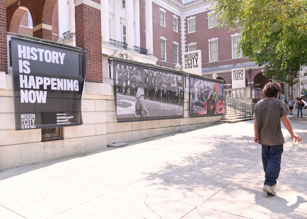 People pass by images from the New York Responds Exhibit at The Museum of the City of New York