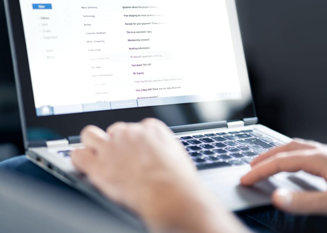 Close view of laptop screen with email inbox open and someone typing.