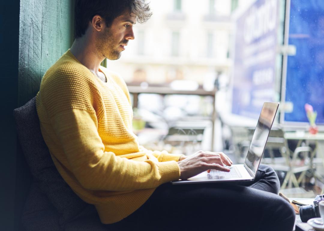 Person sitting in cafe working on laptop.
