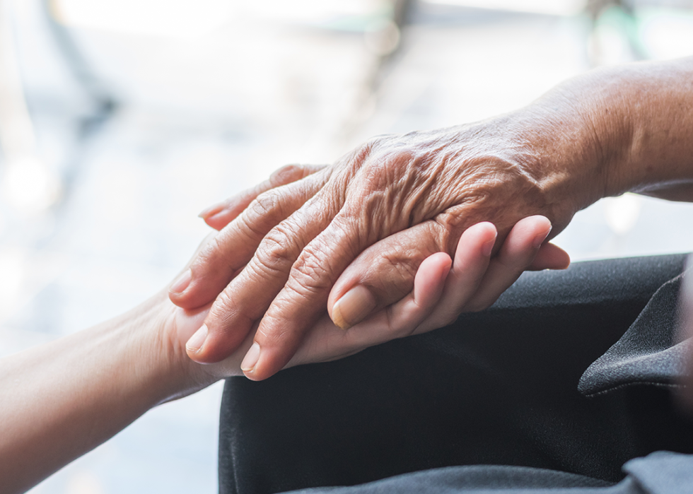 Close up caregiver holding senior hand.