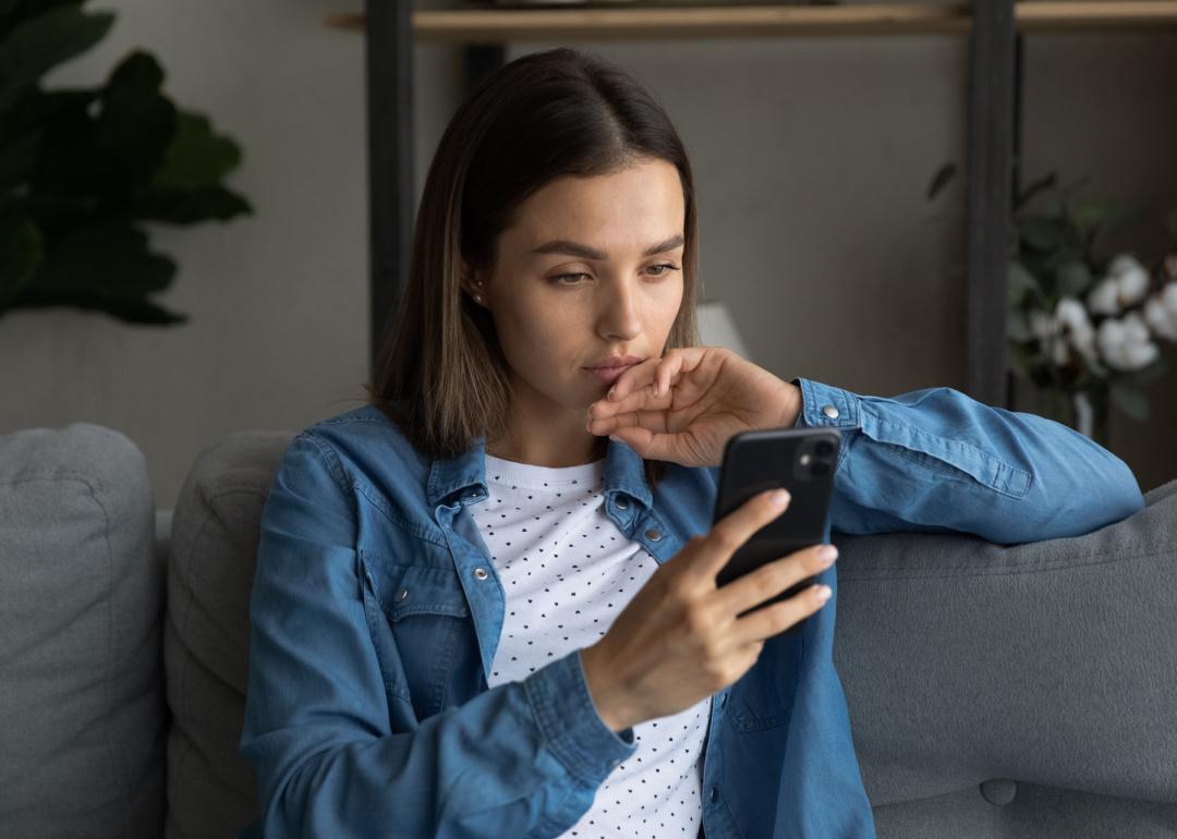 Person looking at phone on sofa.