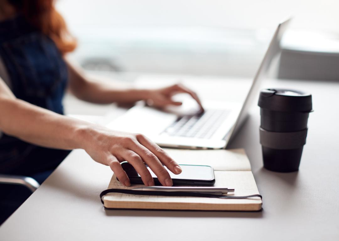 Person reaching for phone at desk.