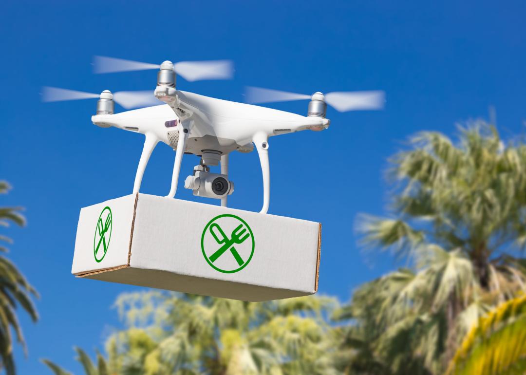 Drone carrying package with food symbol.