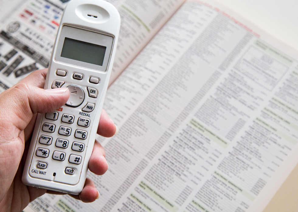 Hand holding phone with White Pages directory open.
