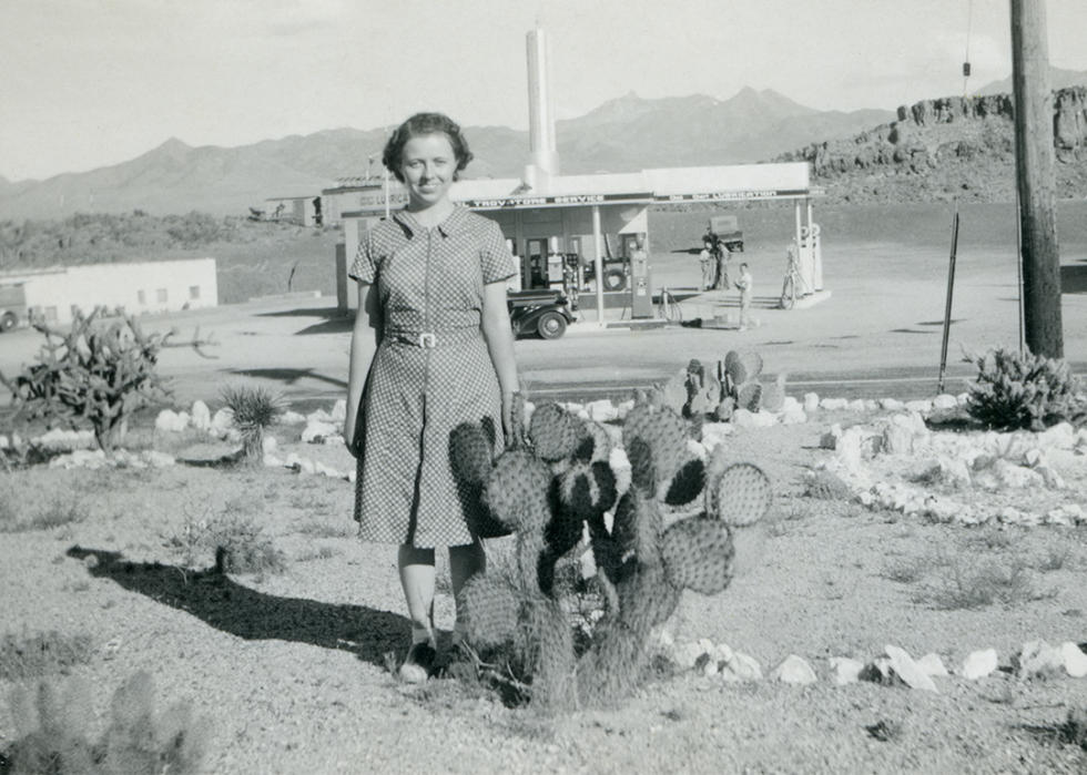 Smiling girl poses with cactus near service station in Arizona.