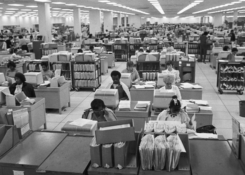 Federal workers process tax forms in a busy office