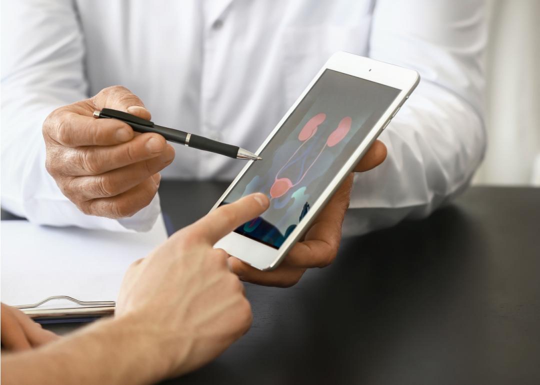 Urologist with tablet computer speaking with patient.