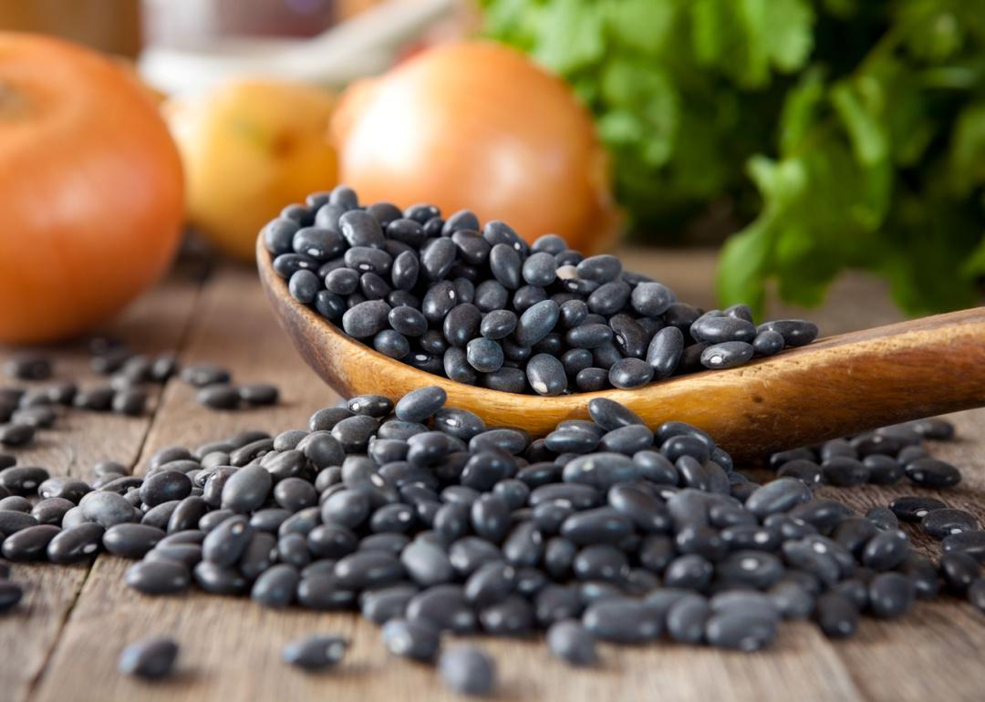 Black beans in a wooden spoon with cilantro and onions.
