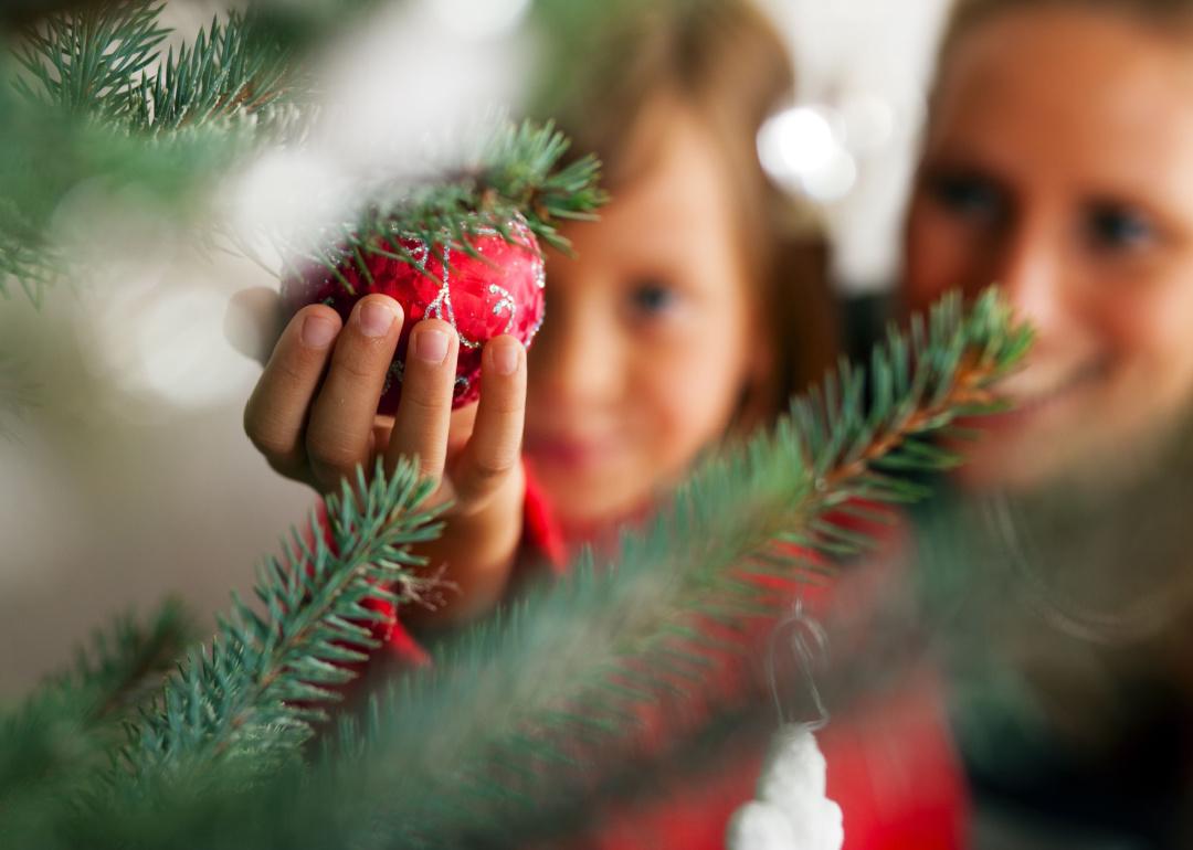 Girl decorating Christmas tree close up on an ornament.
