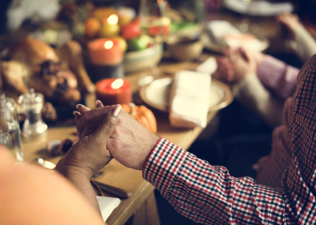 People around Thanksgiving dinner table holding hands.