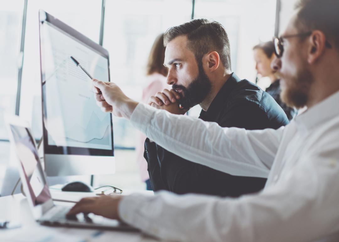 People reviewing reports on screen in office.