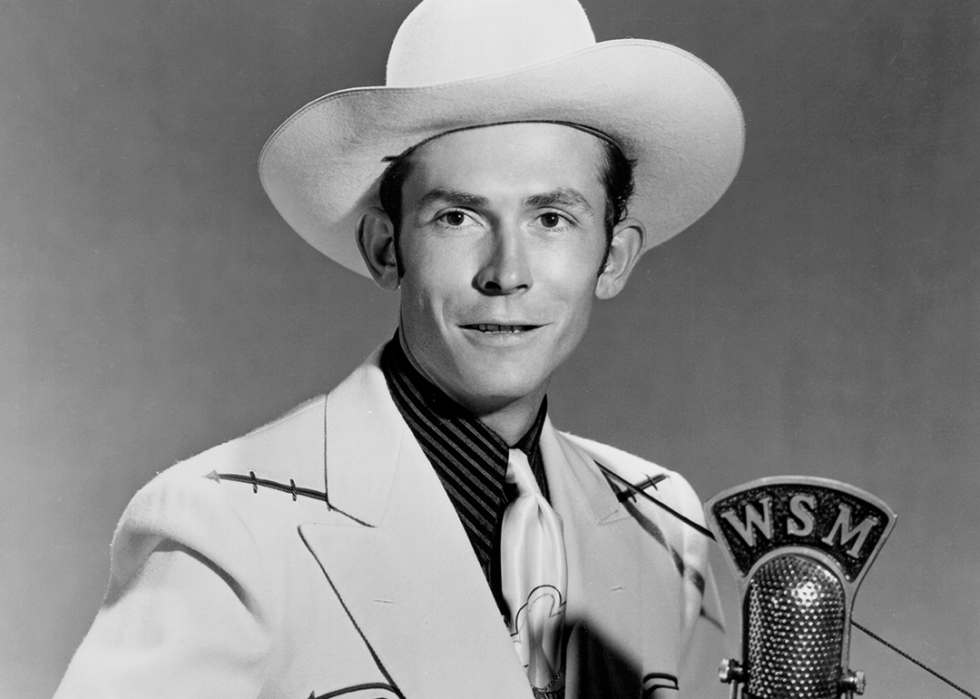 Hank Williams poses for a portrait behind a WSM microphone.