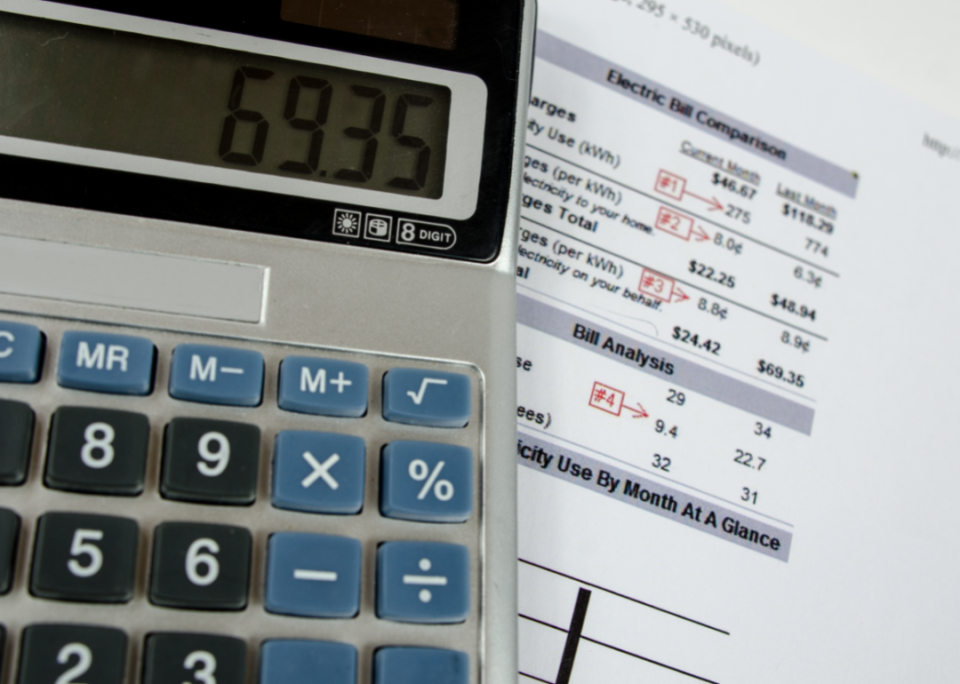 A calculator atop a pile of household utility bills