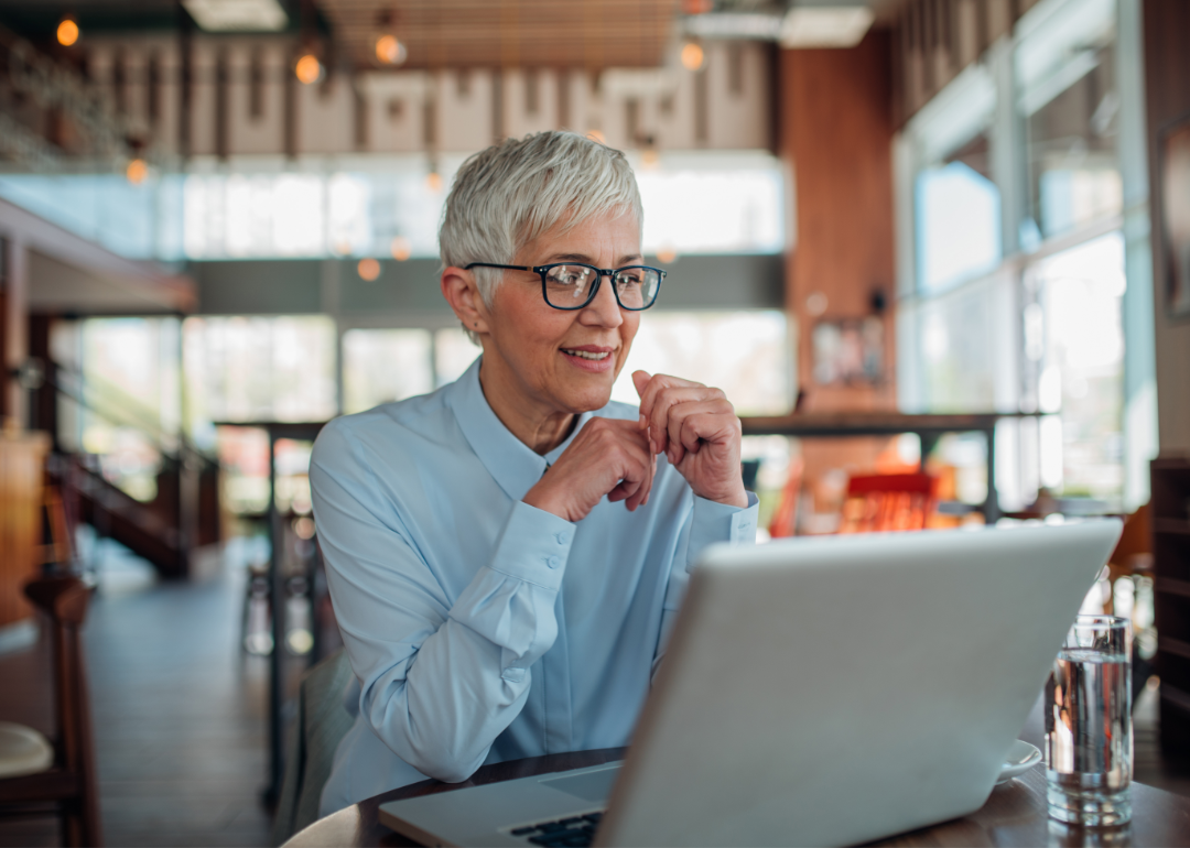 A woman smiles contentedly at her laptop.