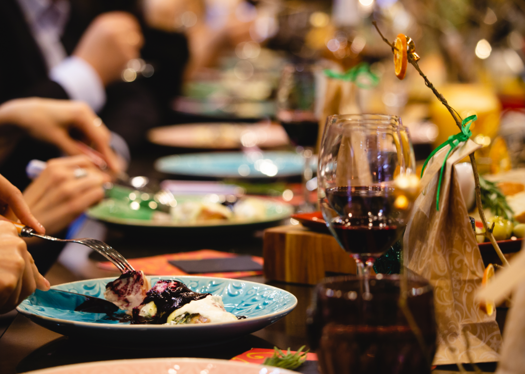 Wine glasses and colorful plates of food at a restaurant.