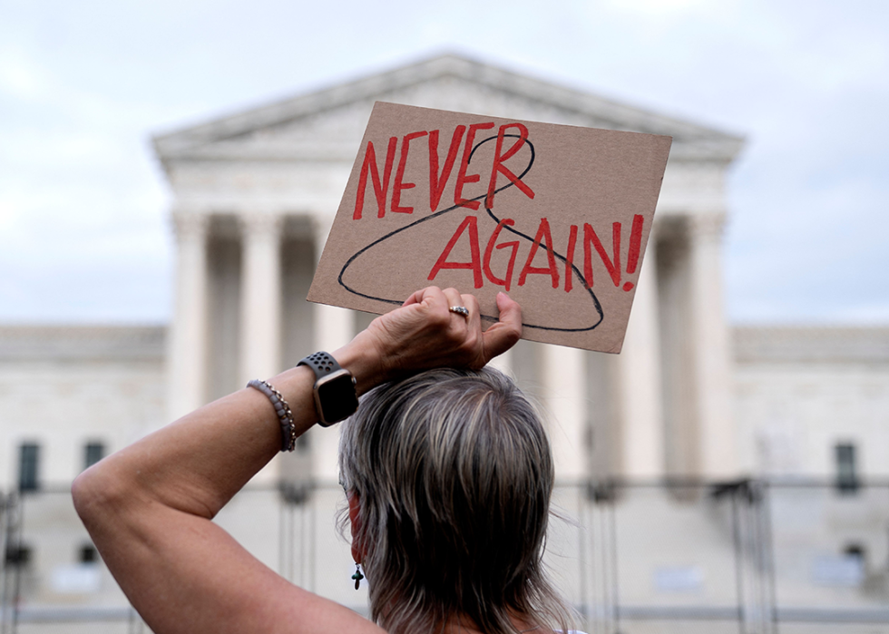 A pro-choice demonstrator holds a sign with a coat hanger with the words Never Again.