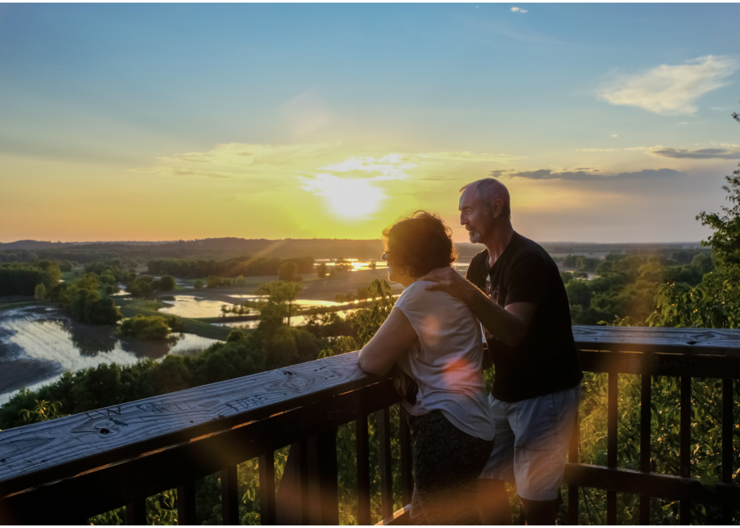 Older couple looking at a sunset from a deck.