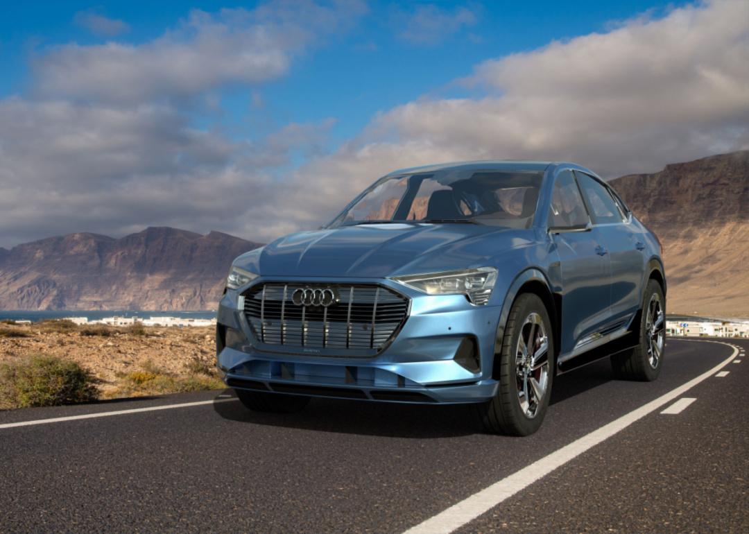 A blue Audi eTron Sportsback drives along desert highway.