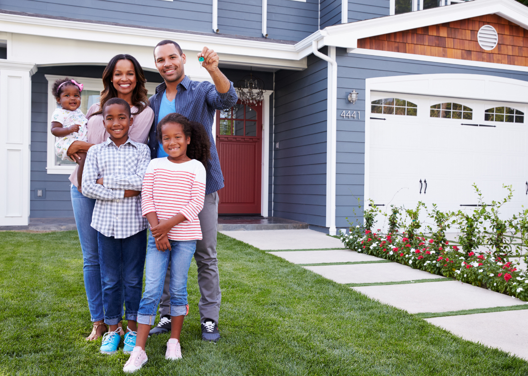 Parents, son, and daughter stand in front of a new home.